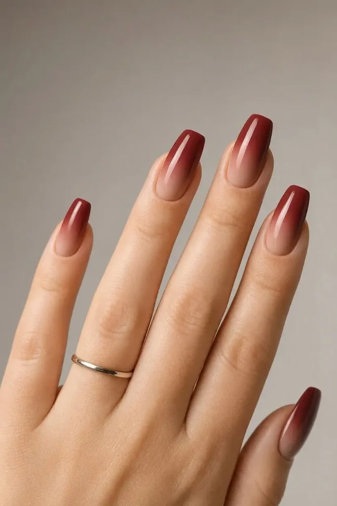 Long coffin nails with a soft ombré fading from nude at the cuticle to burgundy at the tips